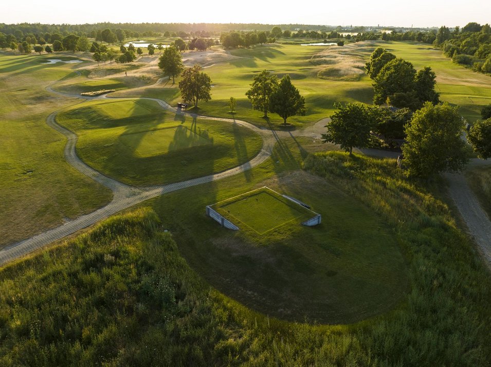 Platz St. Leon Luftaufnahme von Golfabschlägen umringt von grüner Wiese und kleinem Gebäude