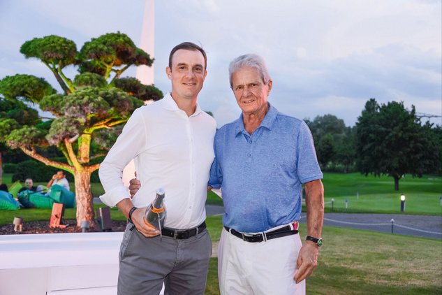 Präsident Daniel Hopp mit Sektflasche in der Hand steht mit Ehrenpräsident Dietmar HoppArm in Arm vor Baum