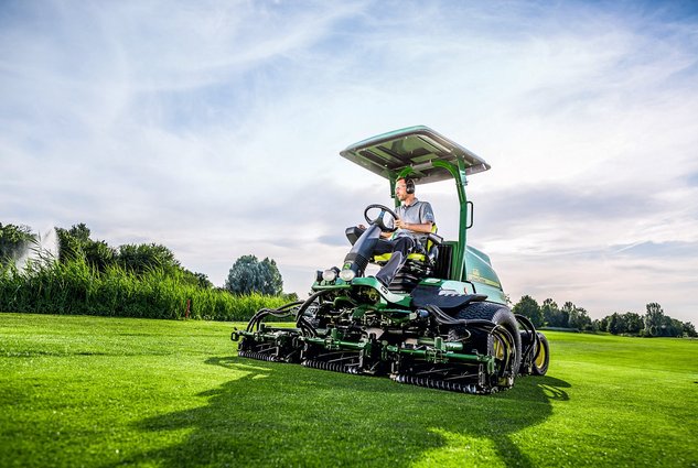 Typische Jobs im Golfsport - Greenkeeper sitzt auf großem Rasenmäher